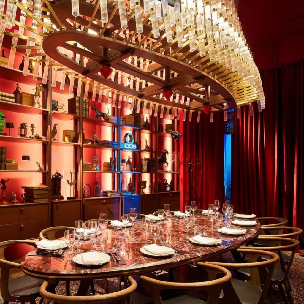 Masa de dining ovala din marmura Rosso Levanto de culoare rosu inchis cu vinisoare albe, amplasata intrun restaurant elegant Fratelli